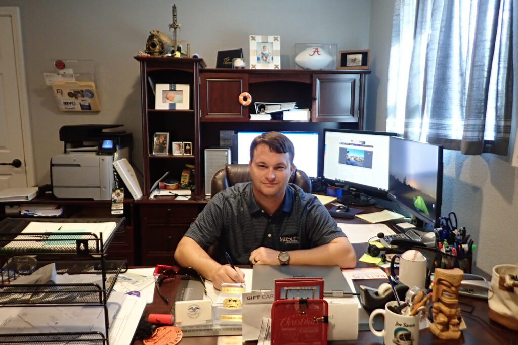 A man sitting at his desk in front of two computers.