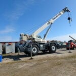 A crane is parked in the dirt near other cranes.