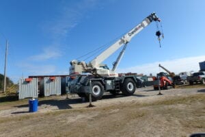 A crane is parked in the dirt near other cranes.