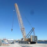 A large crane is in the middle of a dock.